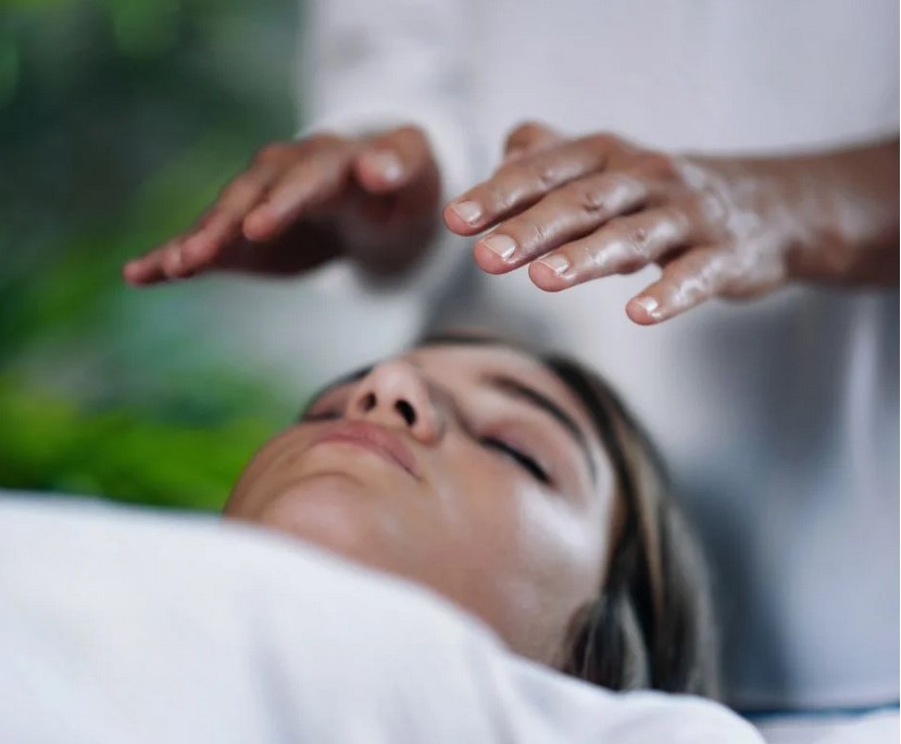 A girl receiving a Pranic Healing treatment, with two hands restoring the energy field of her body and removing blockages for better health and well-being.
